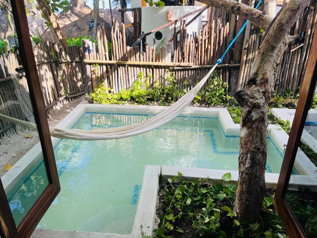 A hammock is hanging over a small swimming pool.