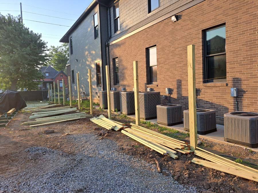 A row of wooden posts are sitting in front of a brick building.