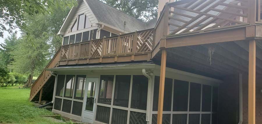 A house with a screened in porch and a deck.