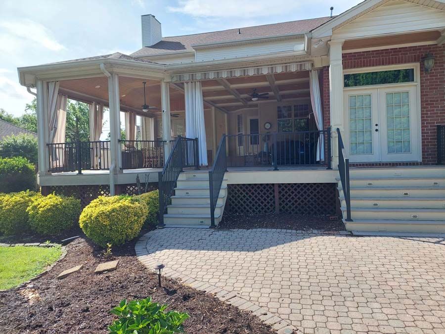 A large brick house with a large porch and stairs leading up to it.
