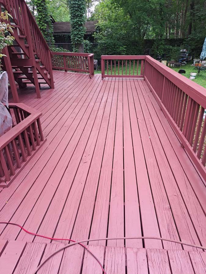 A red wooden deck with stairs leading up to it