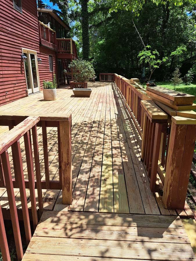 A large wooden deck with a red railing and a house in the background.
