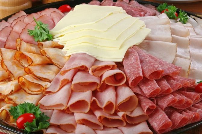 Un assortimento di affettati e formaggi disposti su un piatto con guarnizione di prezzemolo.