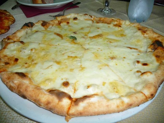 Pizza al formaggio su un piatto bianco a un tavolo da pranzo