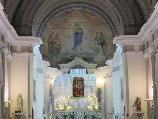 Altare della chiesa riccamente decorato sotto una cupola dipinta, con statue e candele in un santuario illuminato da una luce soffusa.