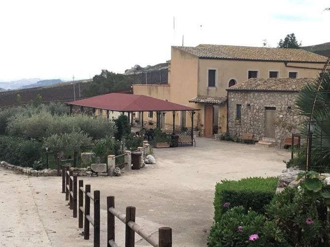 Cortile con edifici in pietra, gazebo con tetto rosso e piante in vaso su un tranquillo patio