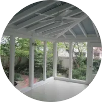 A screened in porch with a ceiling fan and lots of windows.