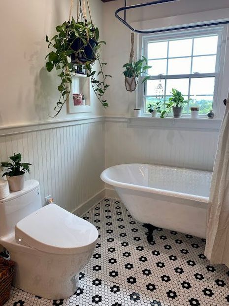 A bathroom with a toilet , tub , and window.