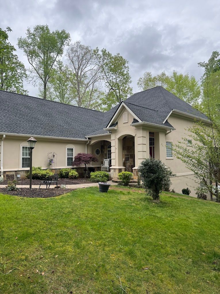 A large house with a gray roof and a large lawn in front of it.