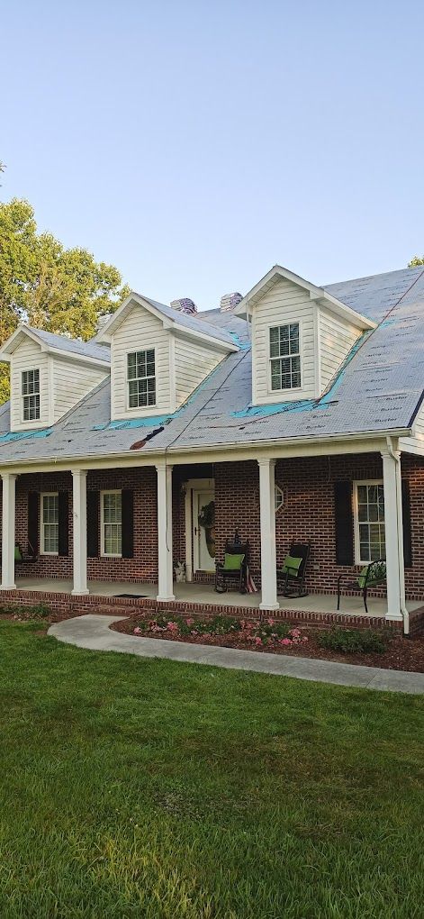 A large brick house with a large porch and a white roof.
