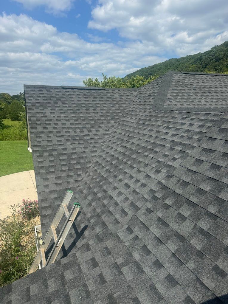 A roof with a lot of shingles on it and a green field in the background.