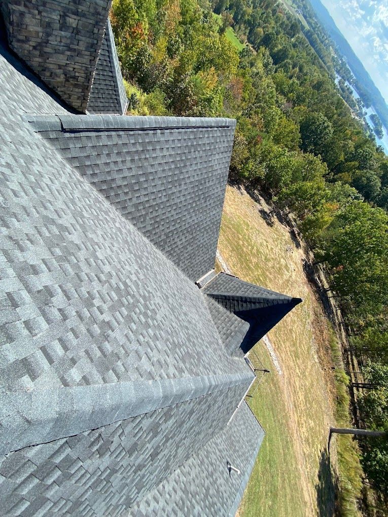A roof with a lot of shingles on it and a green field in the background.