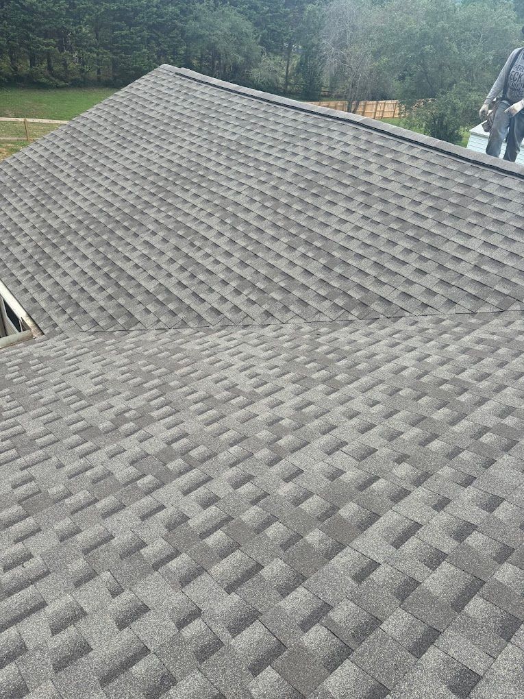 A roof with a lot of shingles on it and a green field in the background.