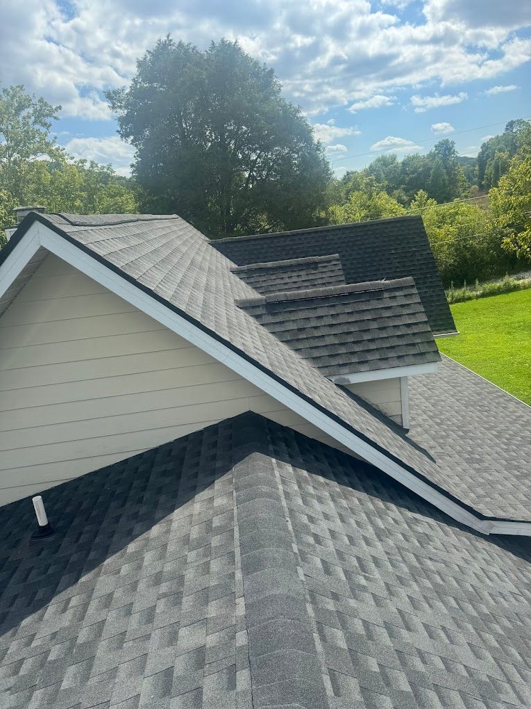 A roof with a lot of shingles on it and a green field in the background.