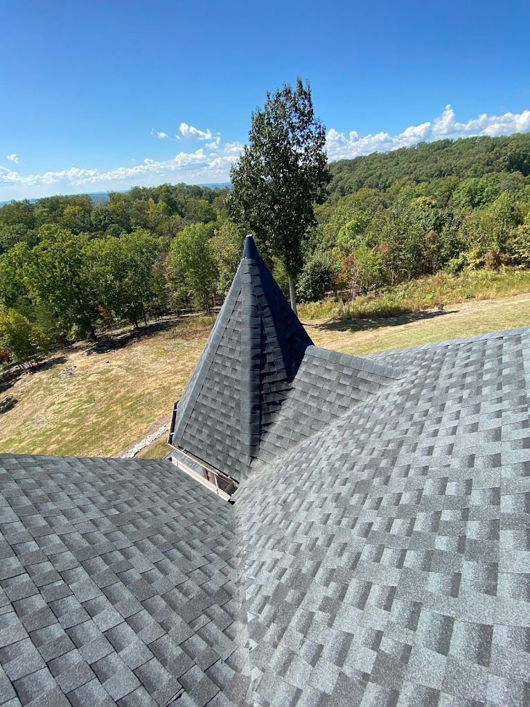 A roof with a lot of shingles on it and a green field in the background.