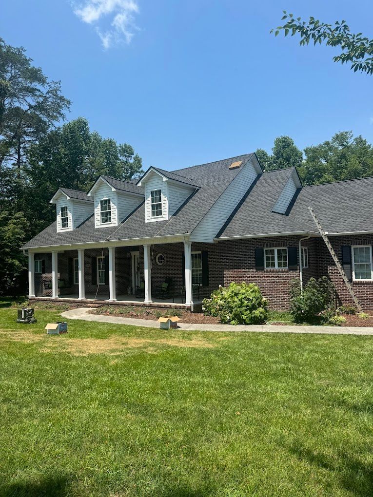 A large brick house with a gray roof and a large porch.
