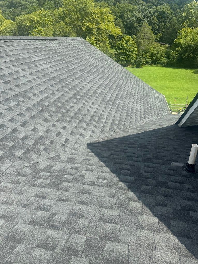 A roof with a lot of shingles on it and a green field in the background.