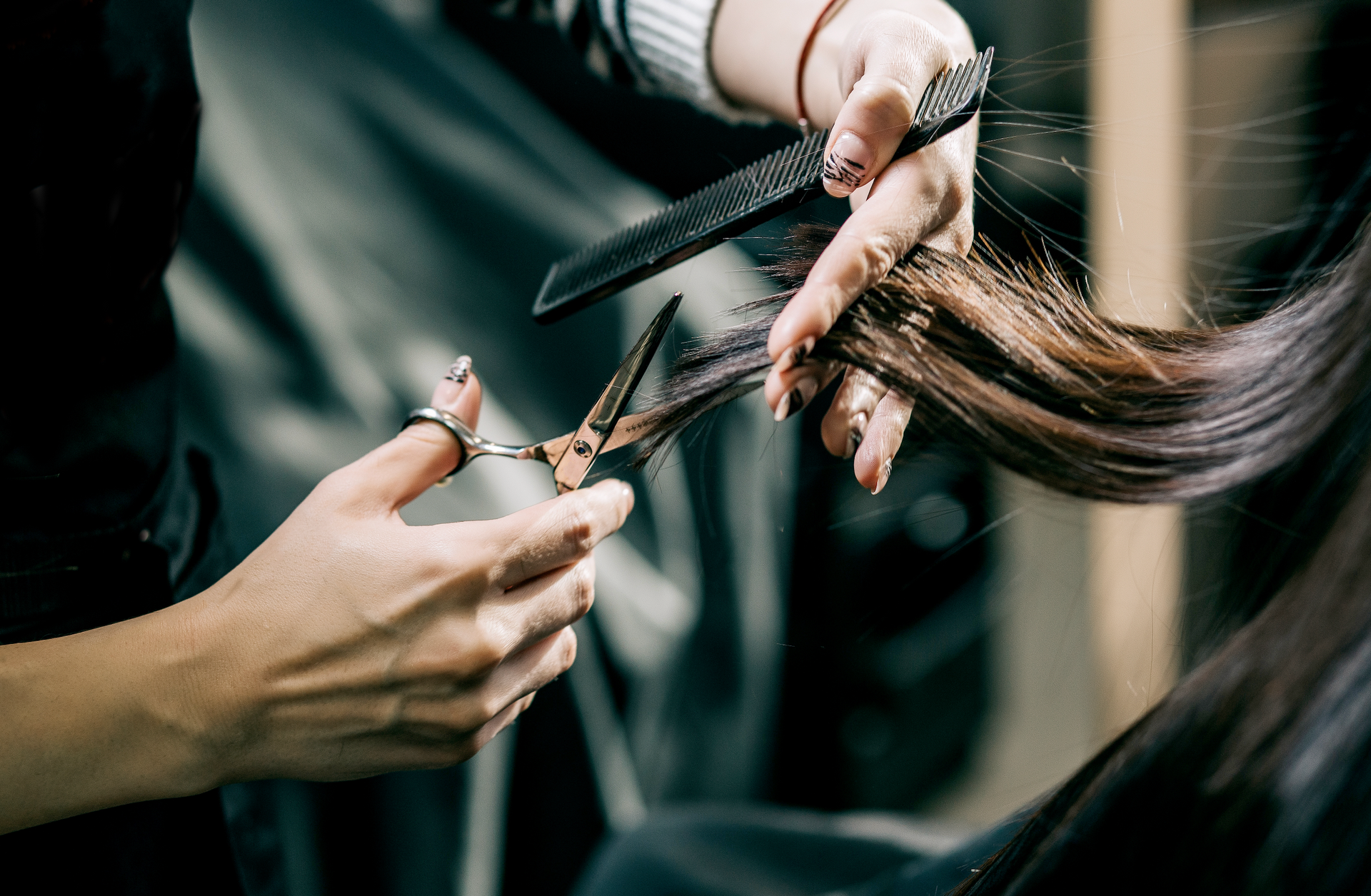 A woman is getting her hair cut by a hairdresser in a salon.