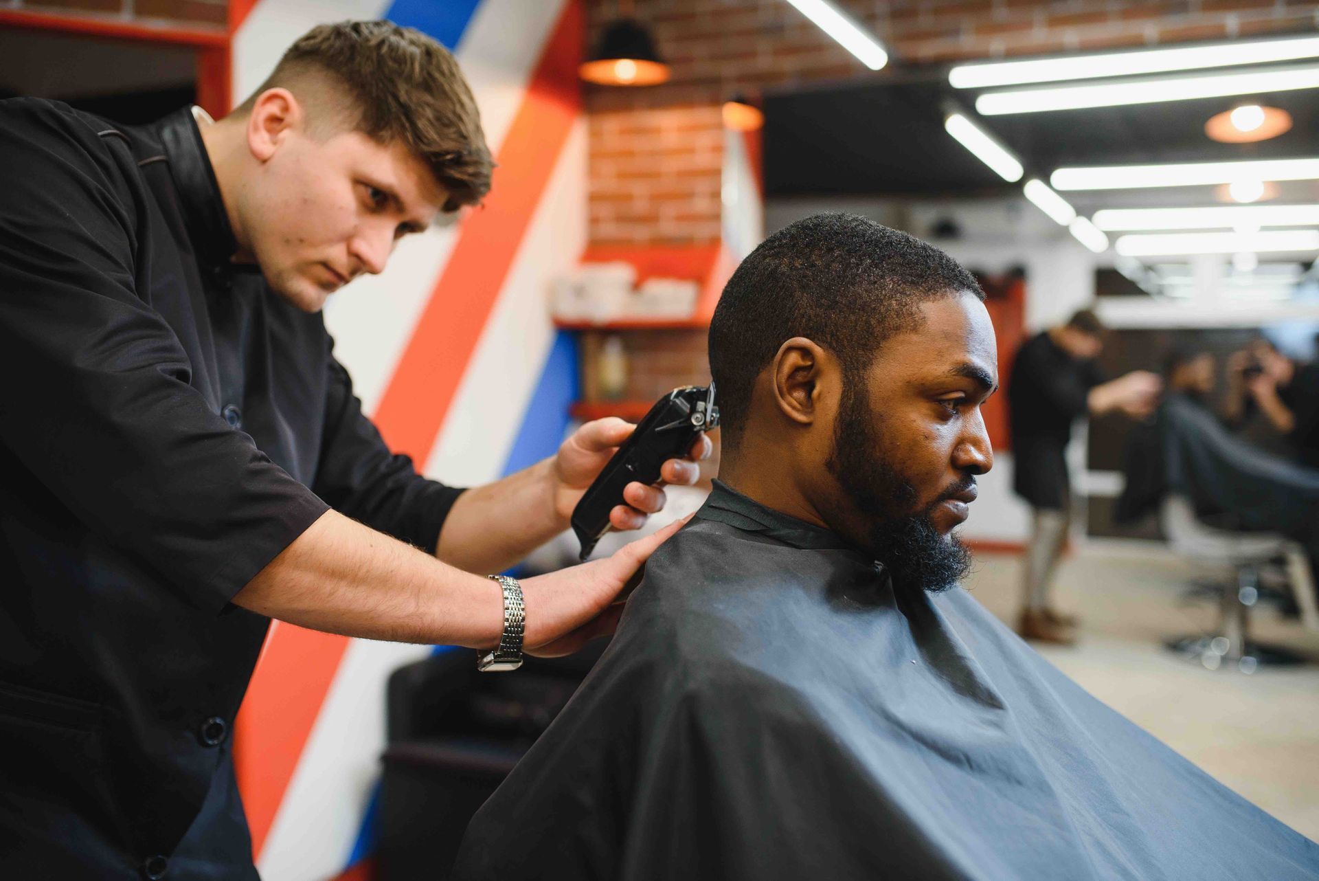 A man is getting his hair cut by a barber in a barber shop.