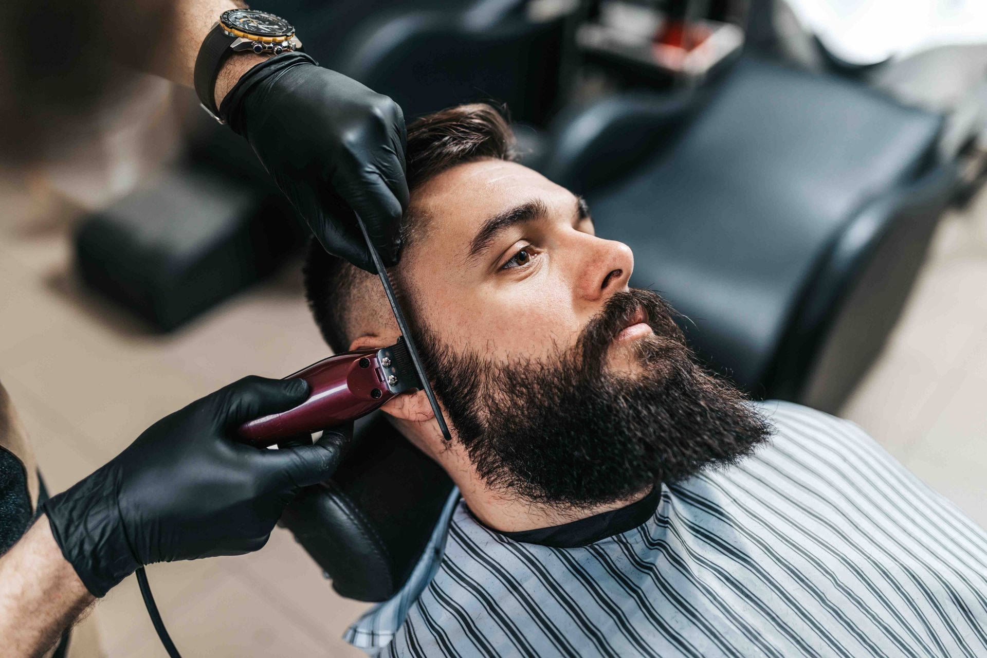 A man with a beard is getting his hair cut by a barber.