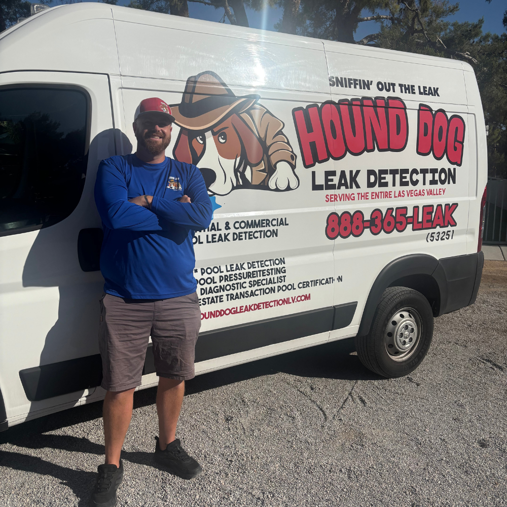 Man posing beside a white Hound Dog Leak Detection van with large red and black signage.