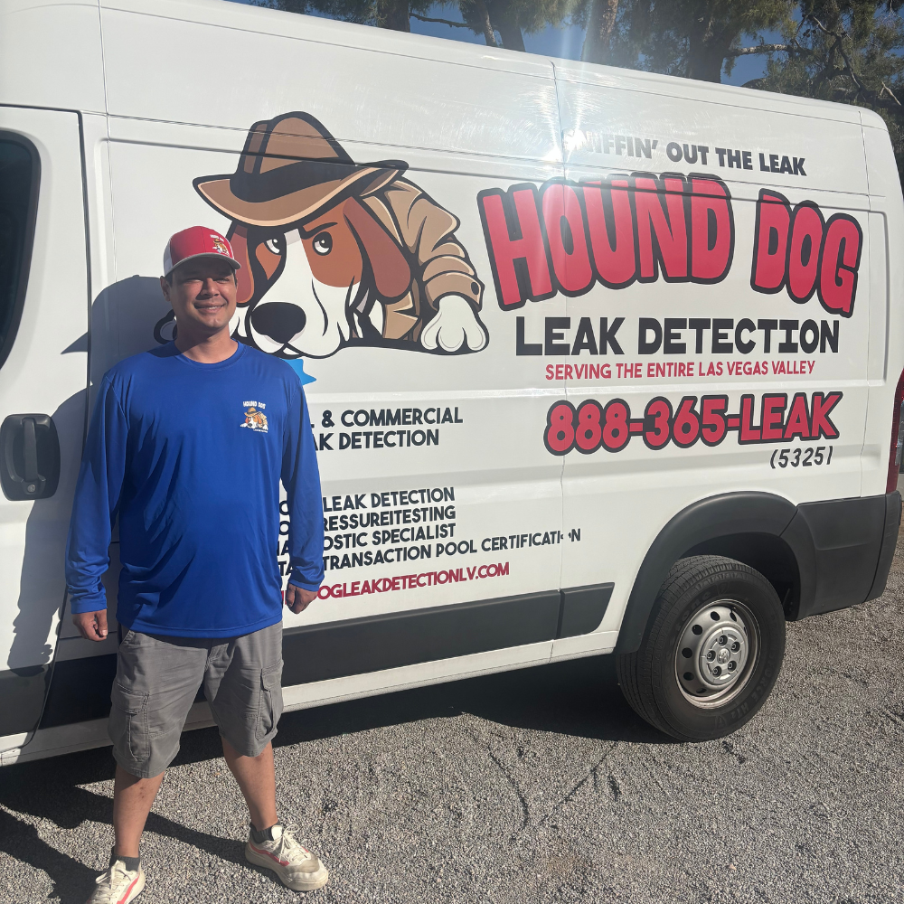 Man standing beside Hound Dog Leak Detection service van with dog logo and large red lettering