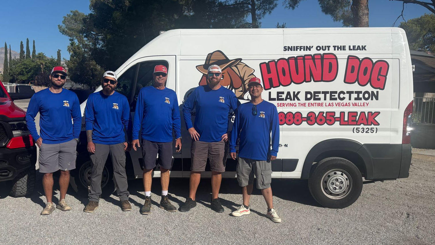 Five people in blue shirts standing in front of a white van with a cartoon logo.