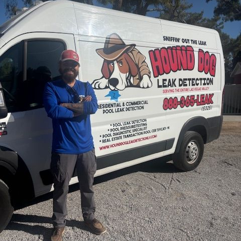 Man standing beside white AROUND DOG Leak Detection van with dog logo and blue shirt in a gravel lot