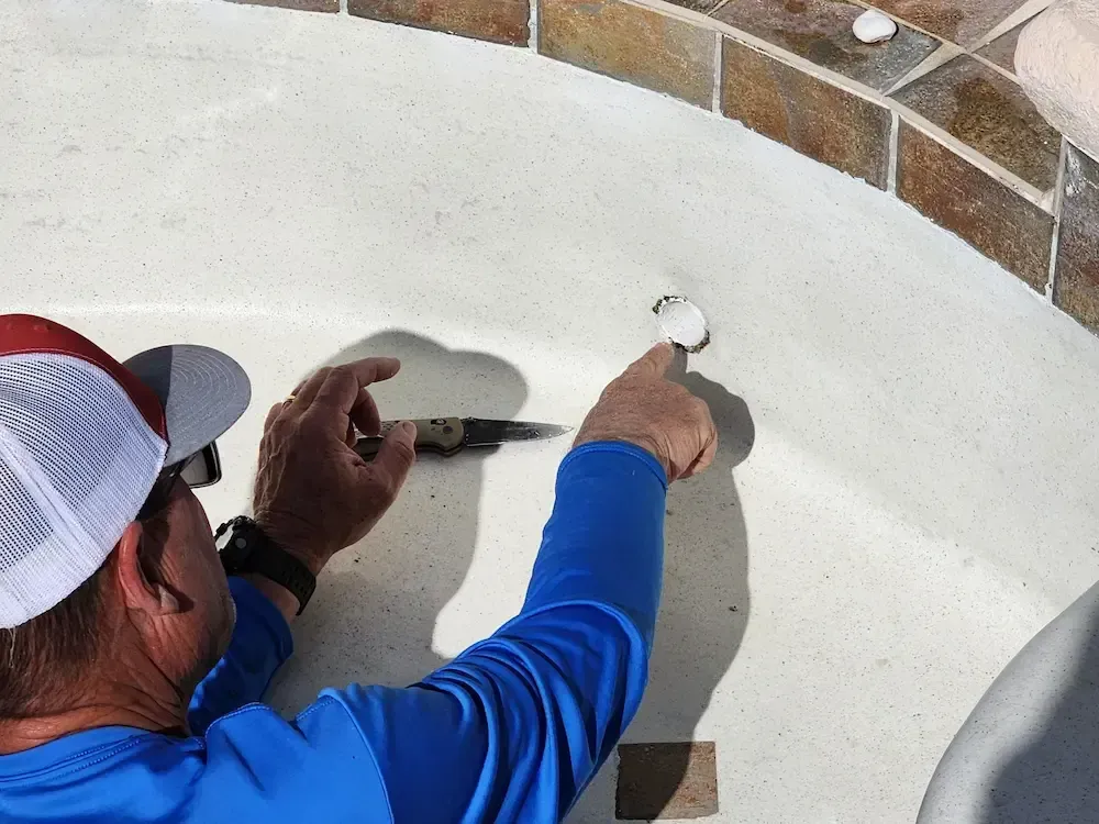 Worker drilling a white concrete surface near a brick edge outdoors