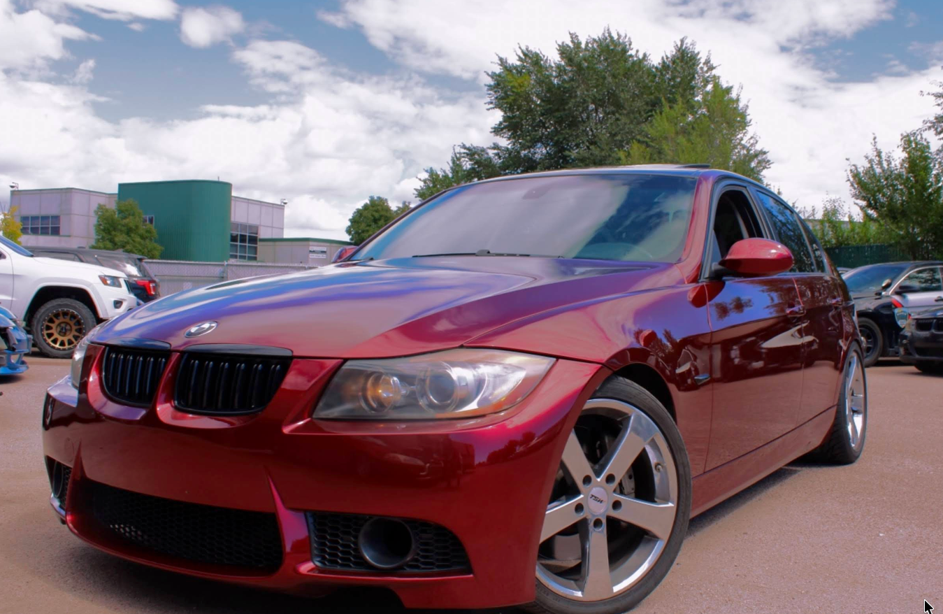 Red BMW sedan with black grille parked outdoors. | Jeanithe Motorsports