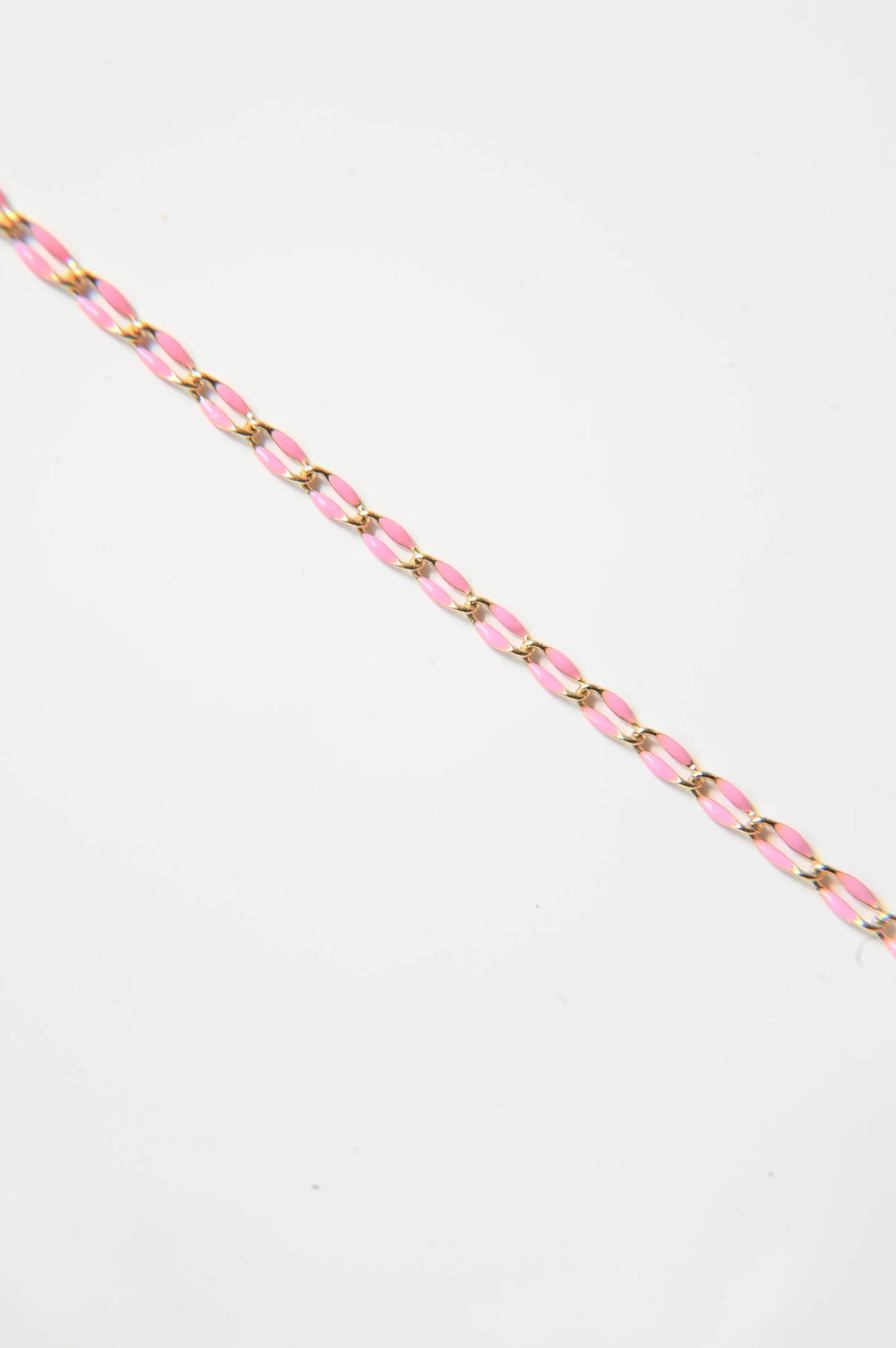 A close up of a pink and gold chain on a white background.