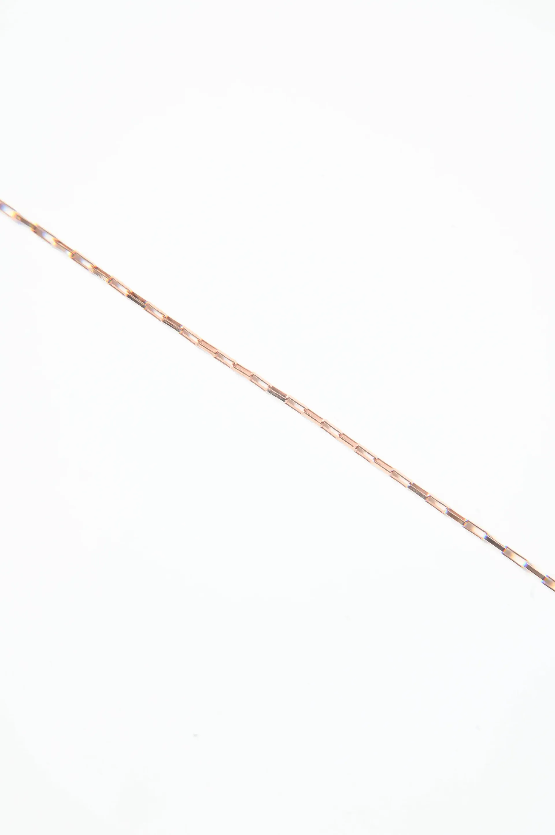 A close up of a gold chain on a white background.