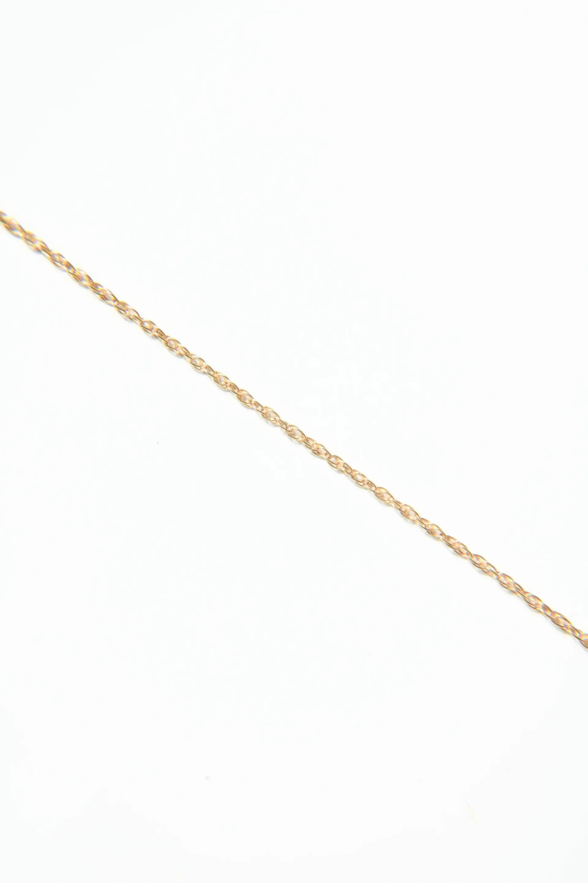 A close up of a gold chain on a white background.