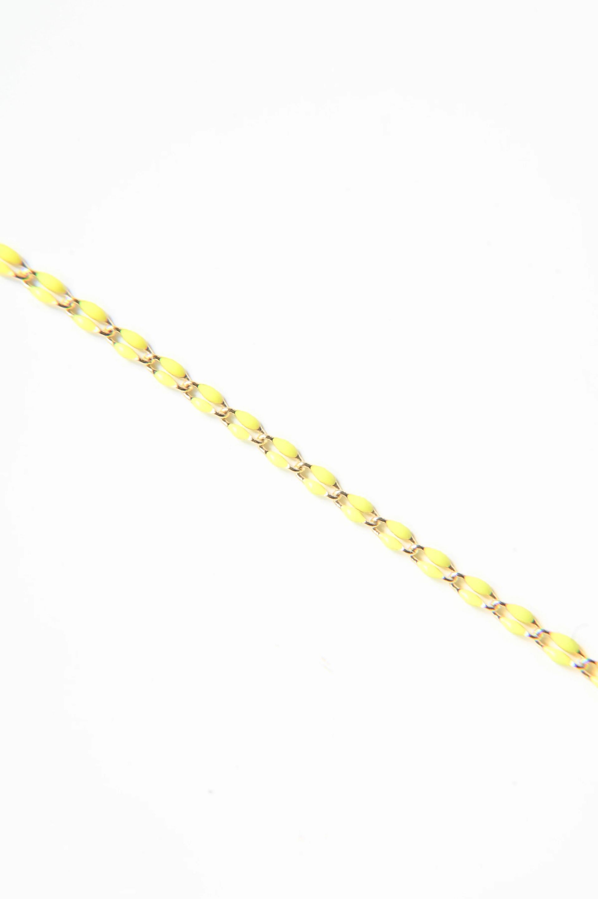 A close up of a yellow bracelet on a white background.