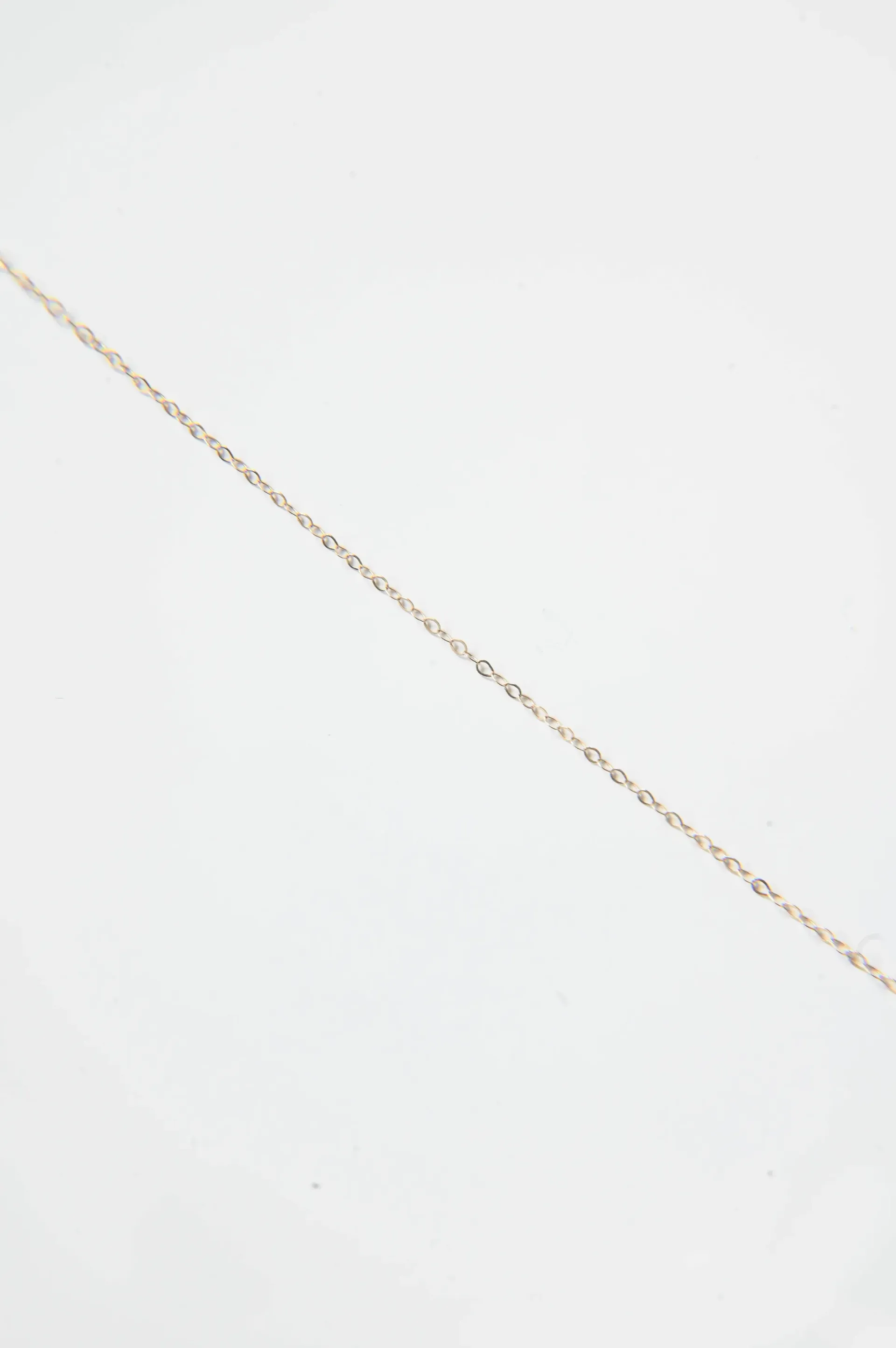 A close up of a gold chain on a white surface.