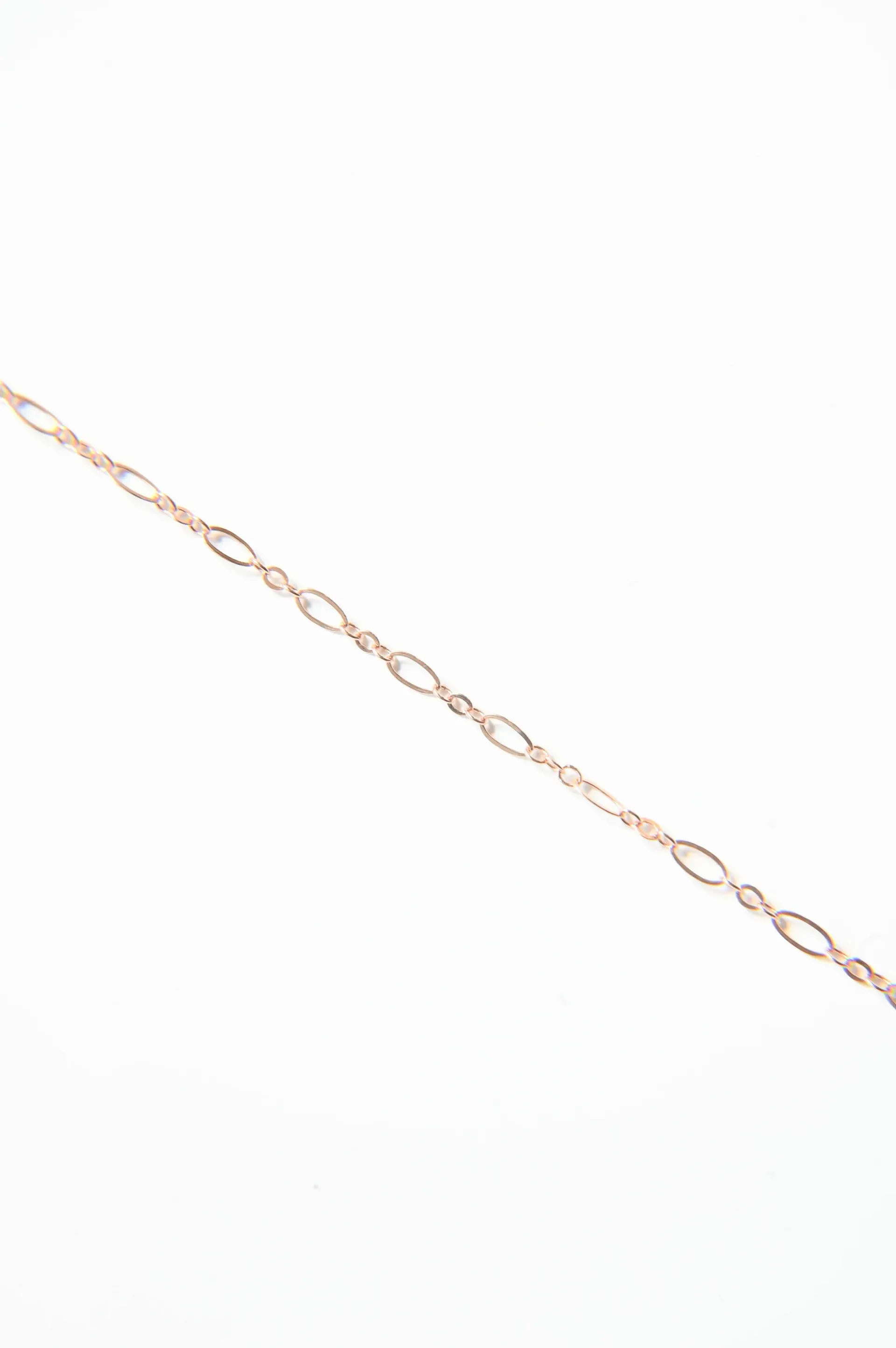 A close up of a gold chain on a white background.