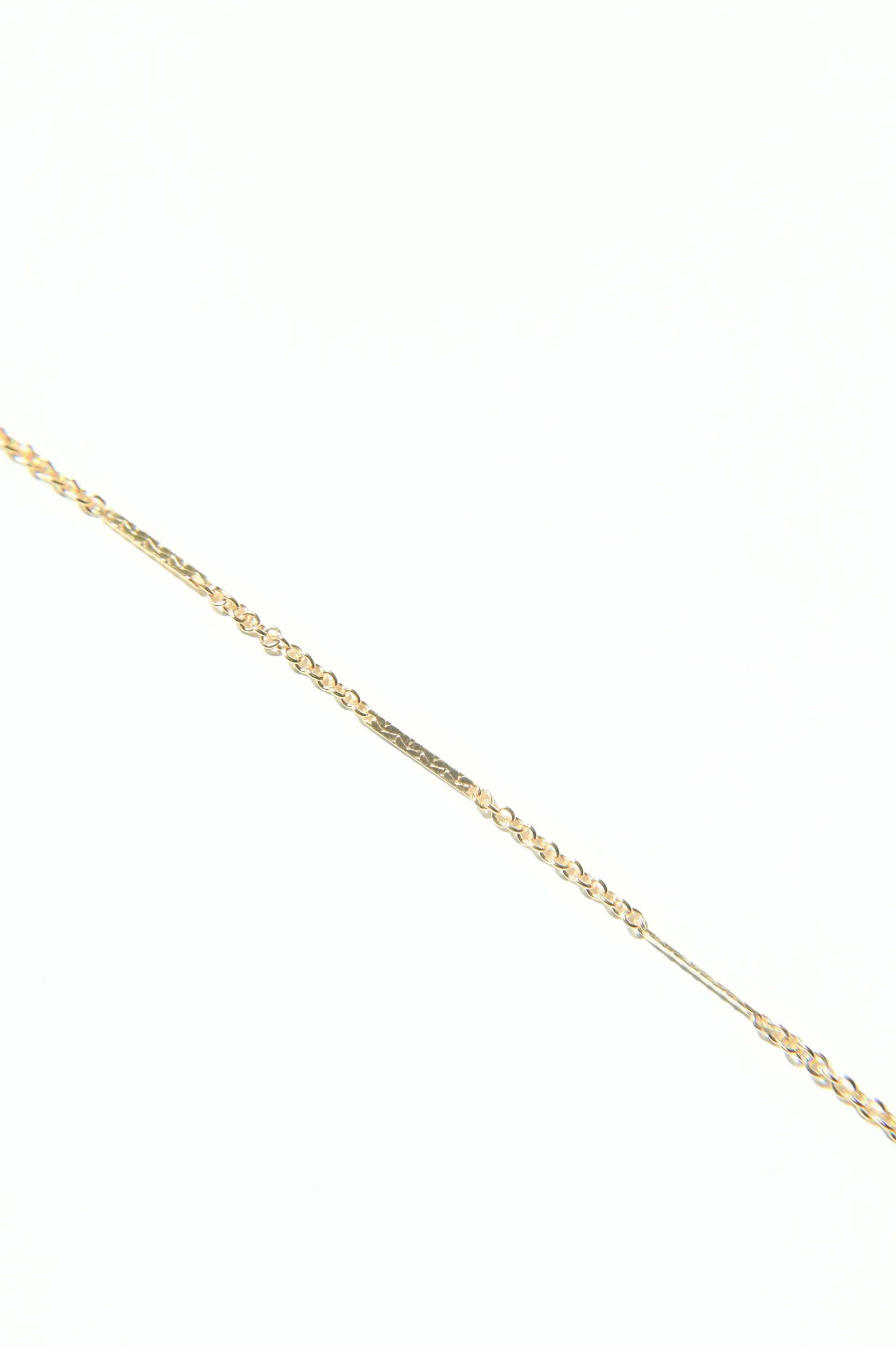 A close up of a gold chain on a white background.
