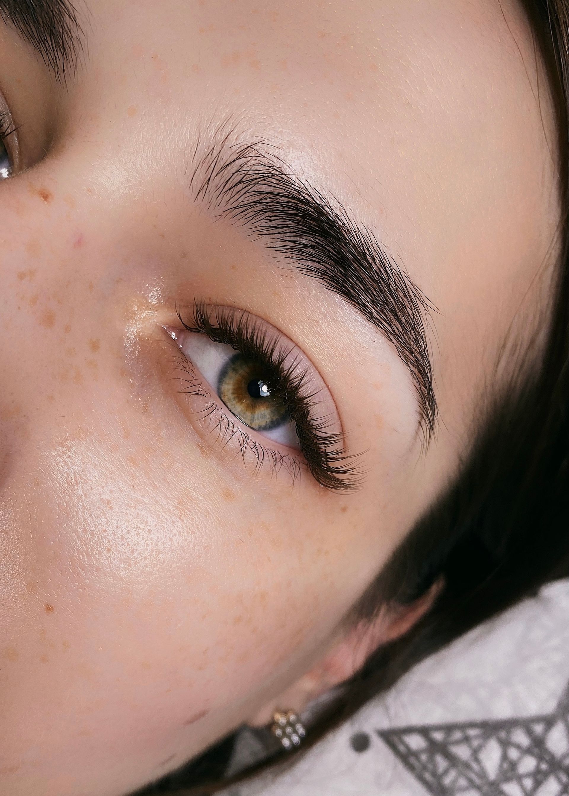 Close-up of a person's eye and eyebrow with microblading. The skin is light, eyes are green-brown.