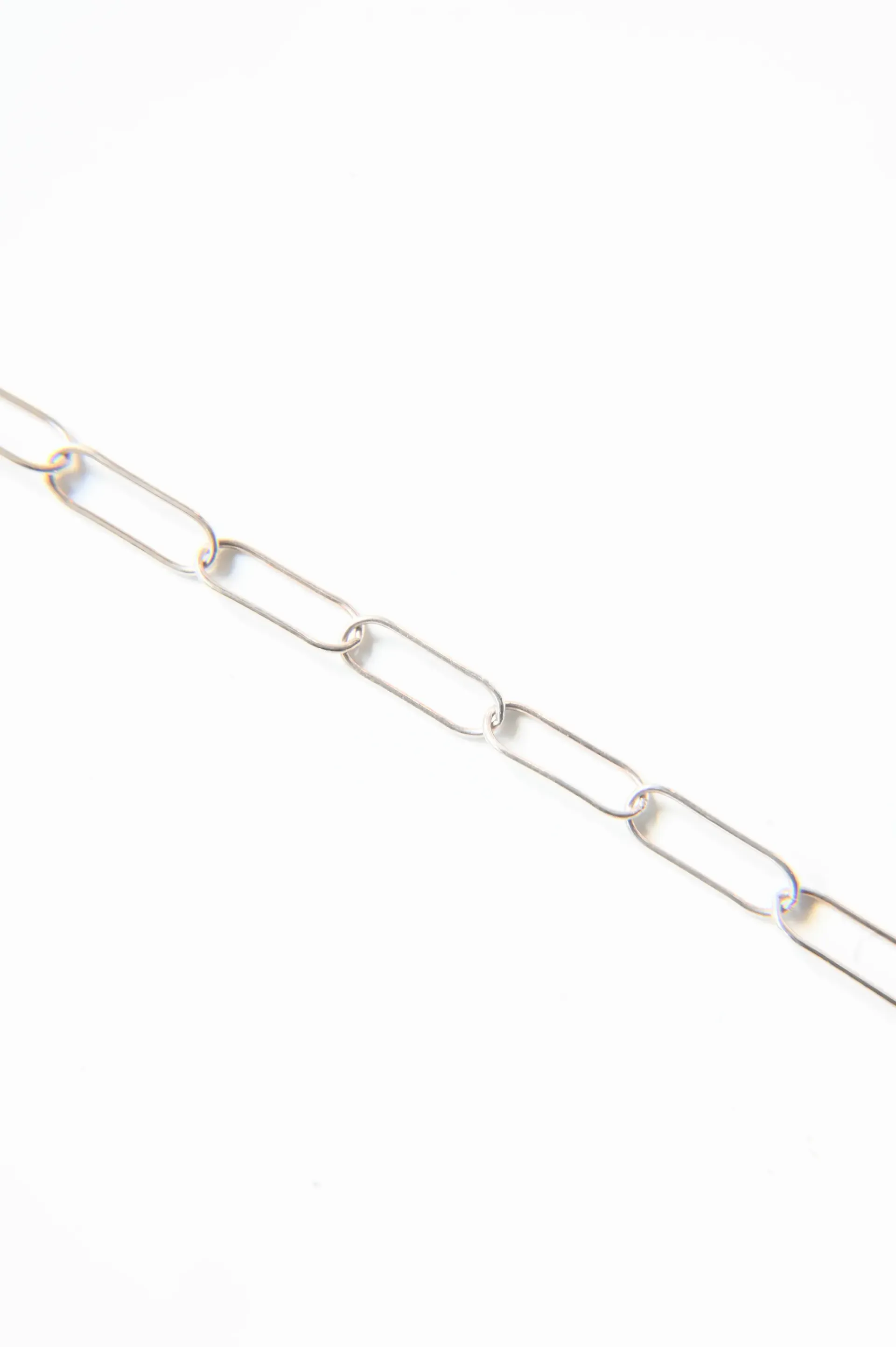 A close up of a gold chain on a white background.