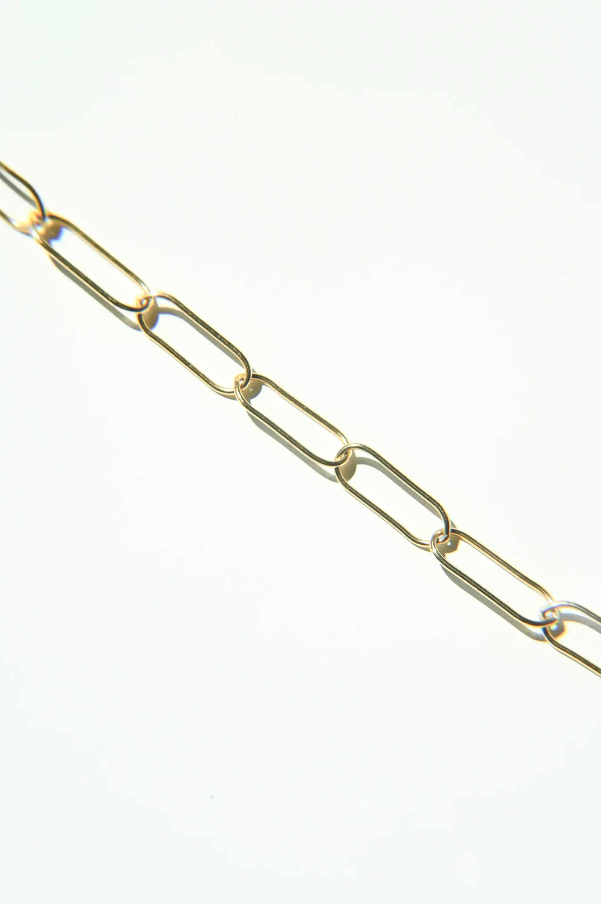 A close up of a gold chain on a white background.