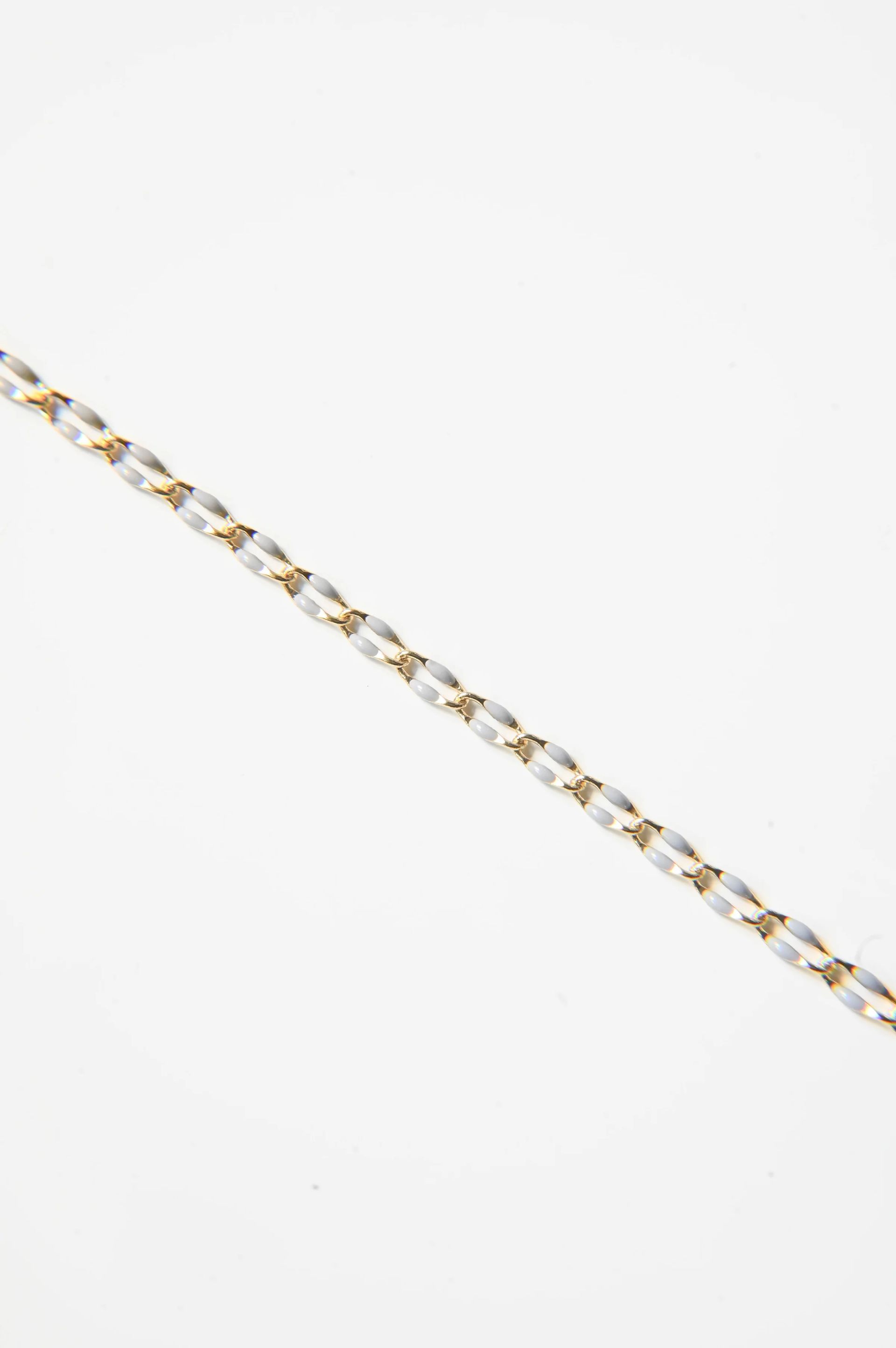 A close up of a gold chain on a white background.