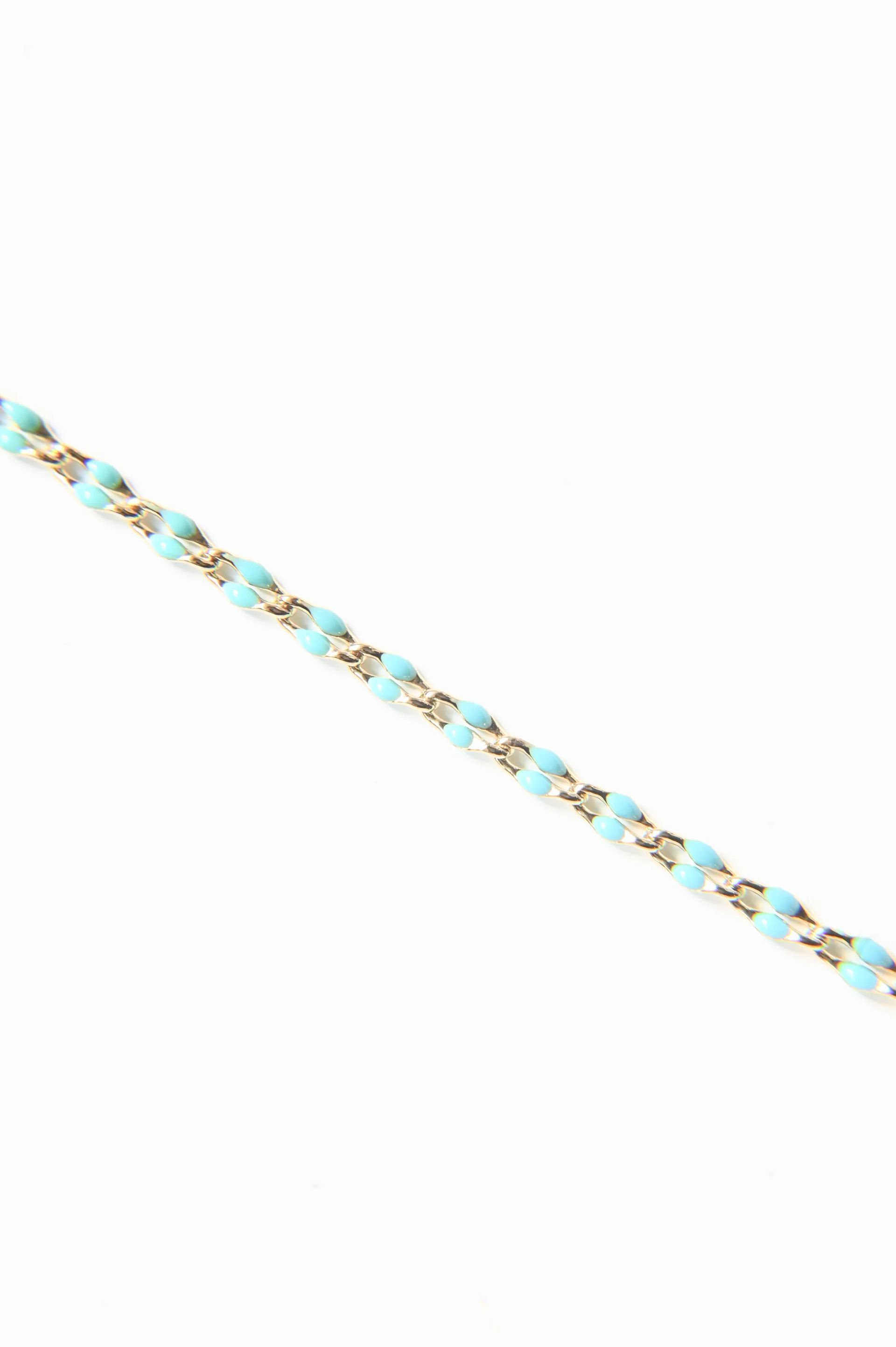 A close up of a turquoise and gold bracelet on a white background.