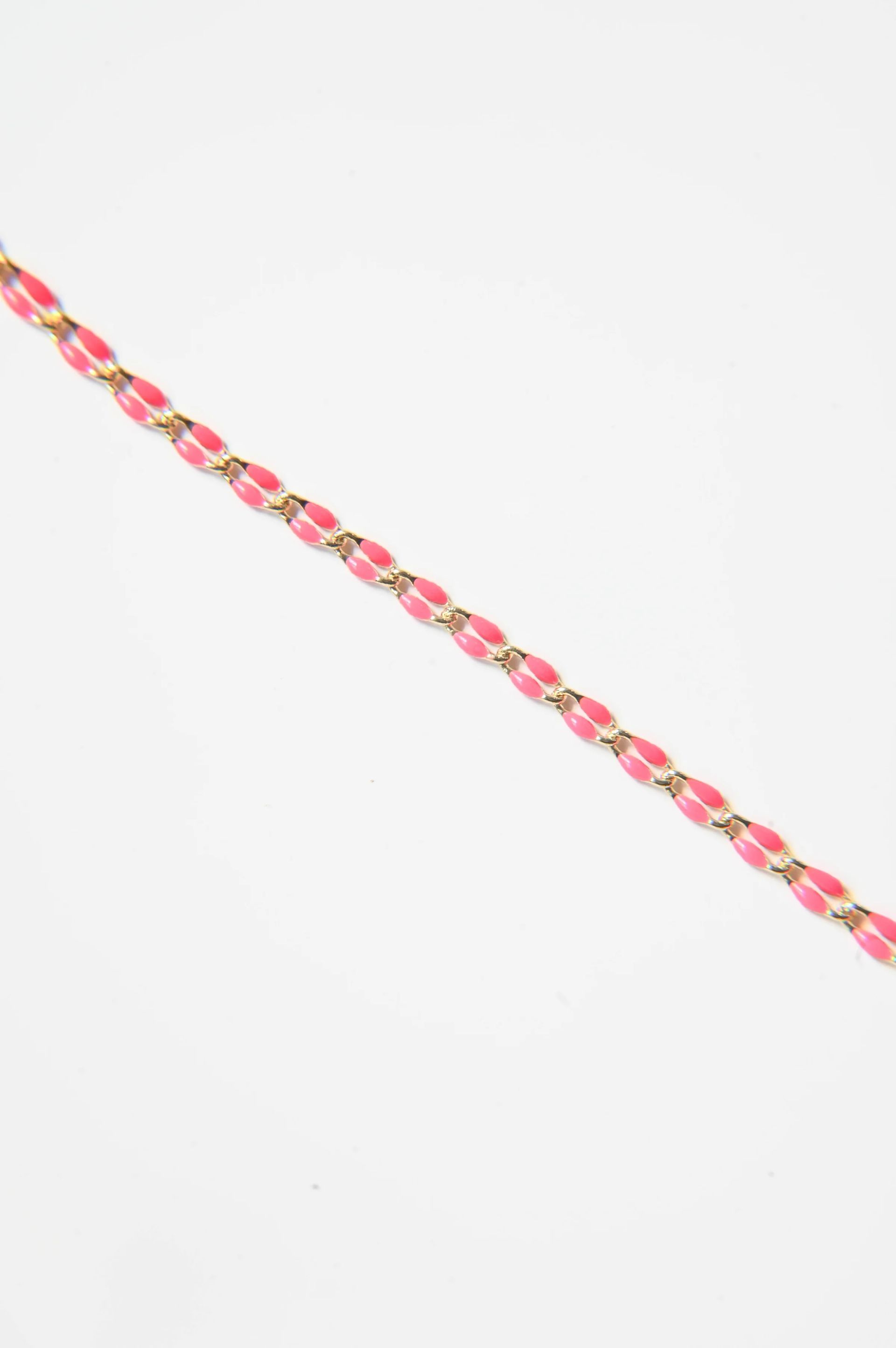 A close up of a pink and gold chain on a white background.