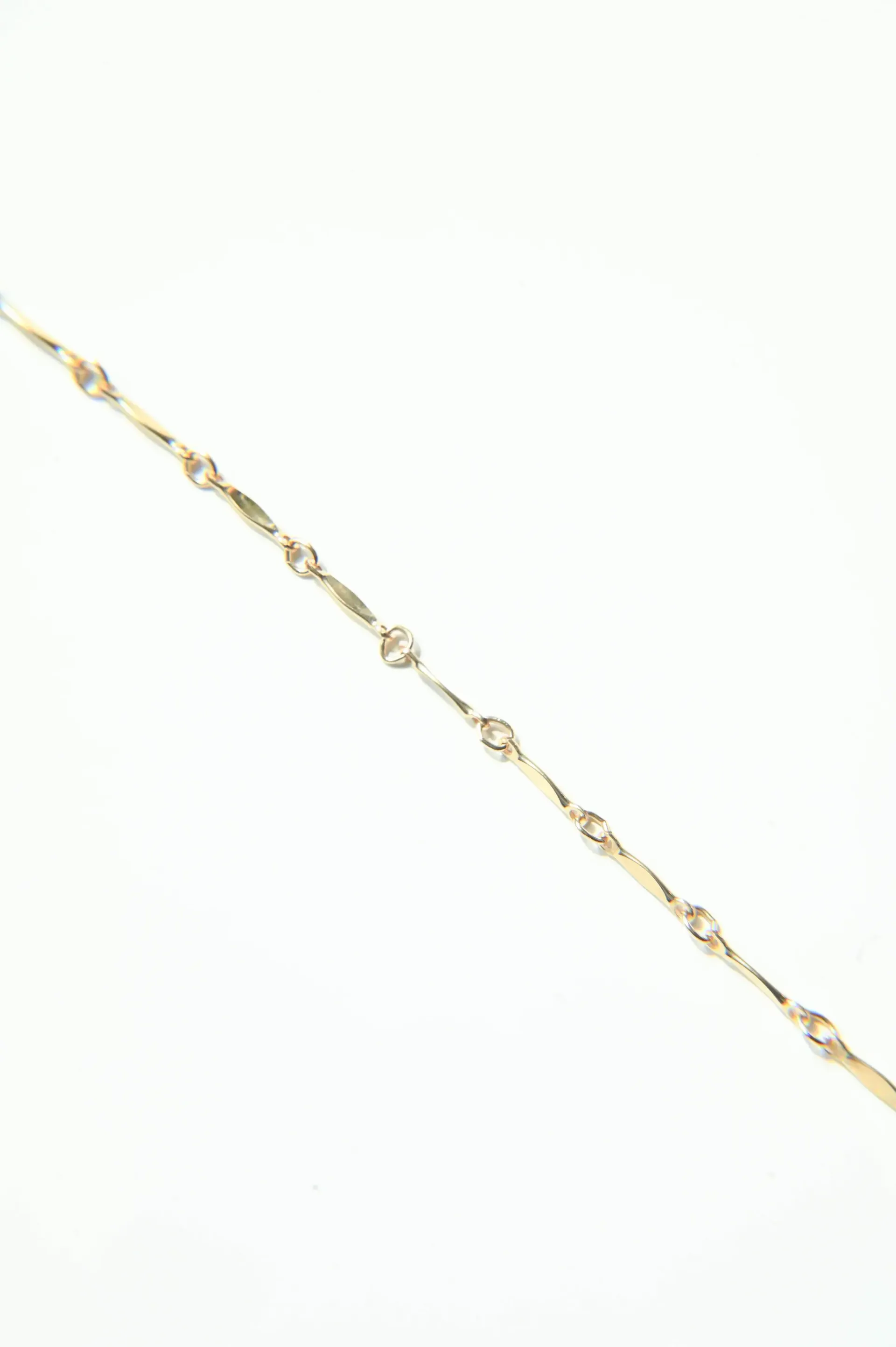 A close up of a gold chain on a white background.