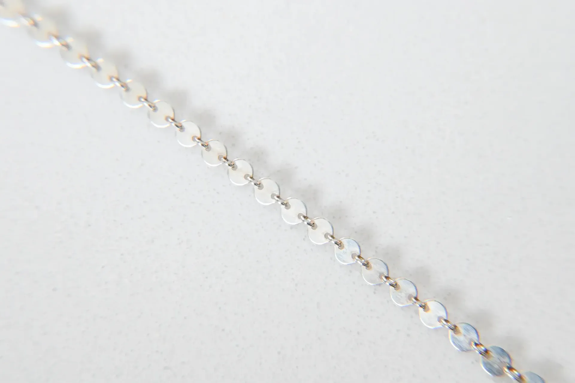 A close up of a chain on a white surface.