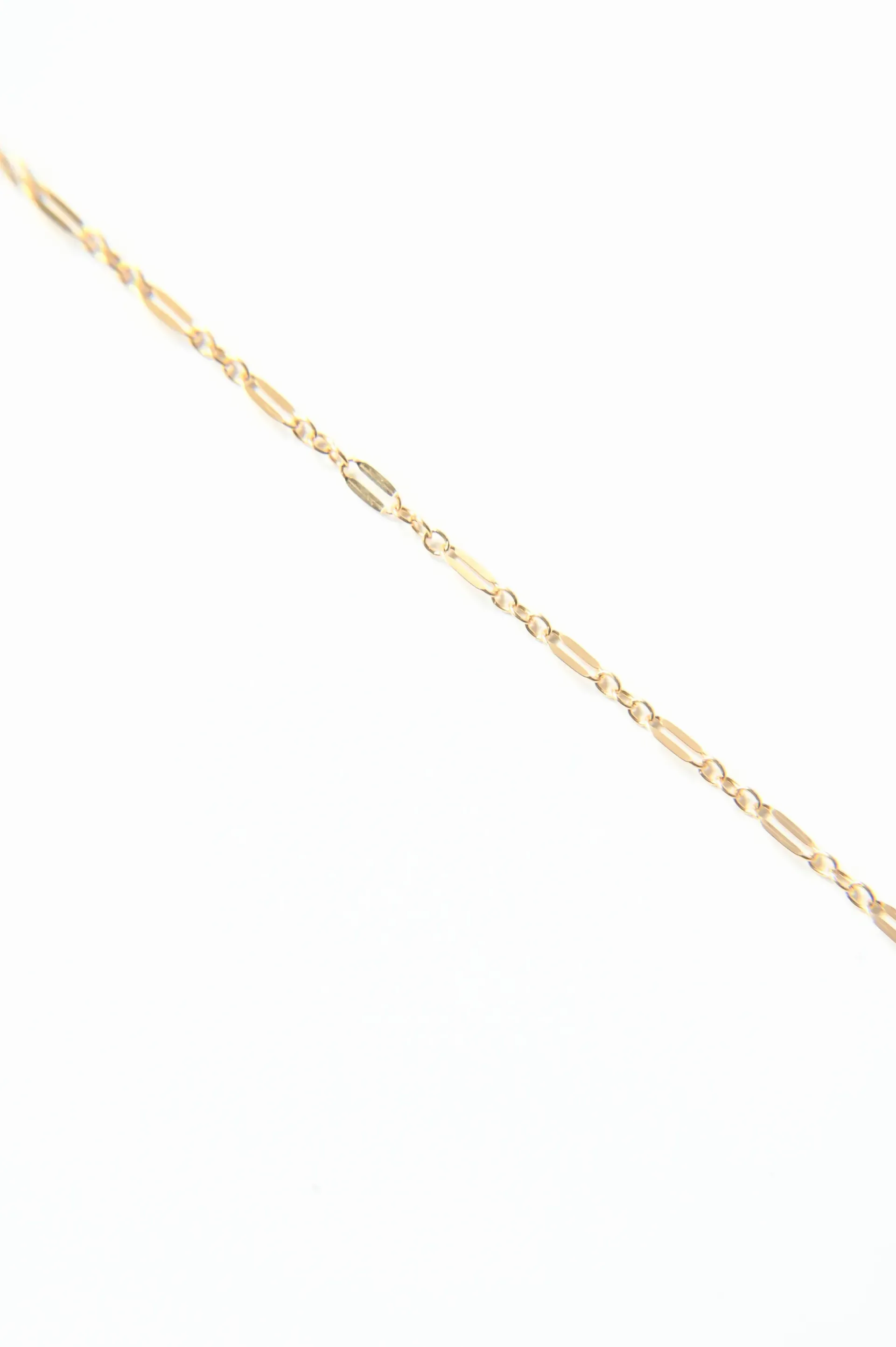 A close up of a gold chain on a white background.