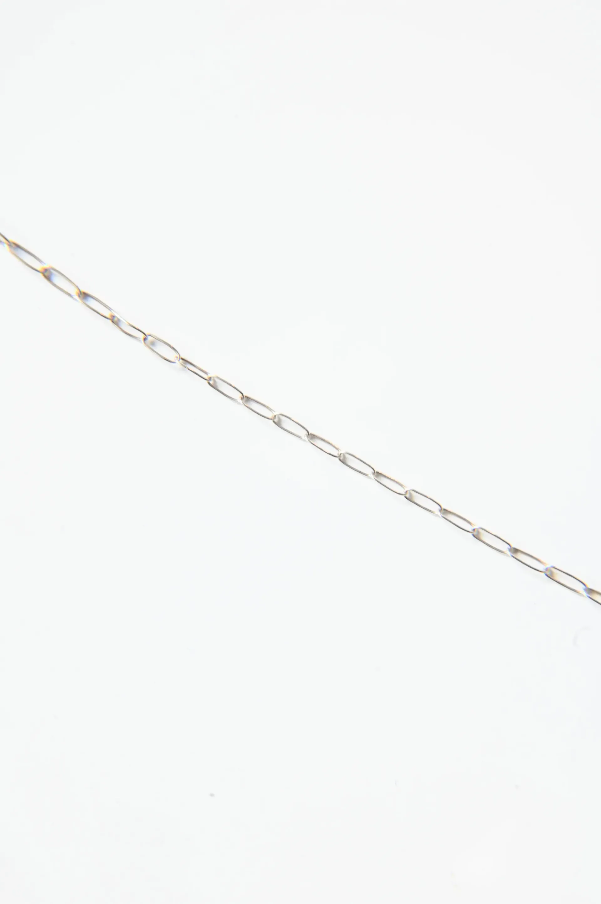 A close up of a silver chain on a white background.