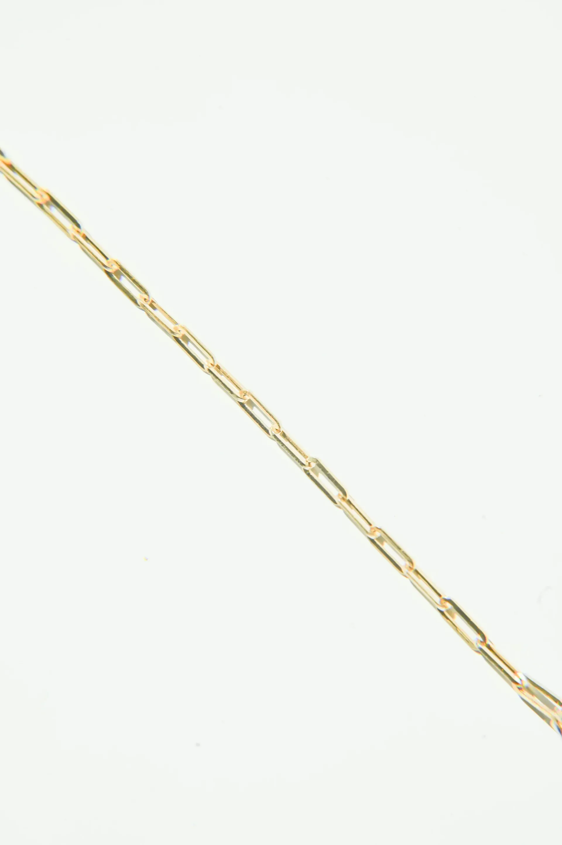 A close up of a gold chain on a white background.