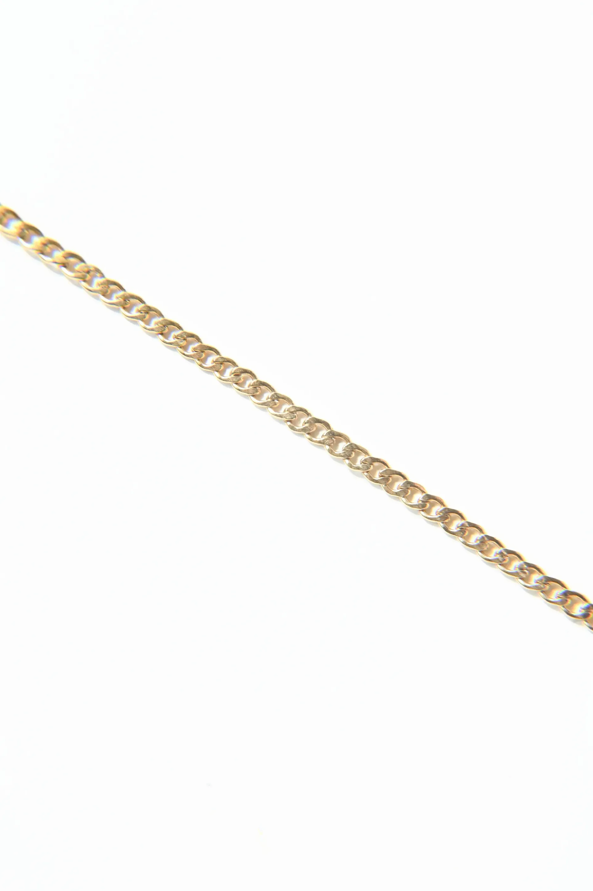 A close up of a gold chain on a white background.