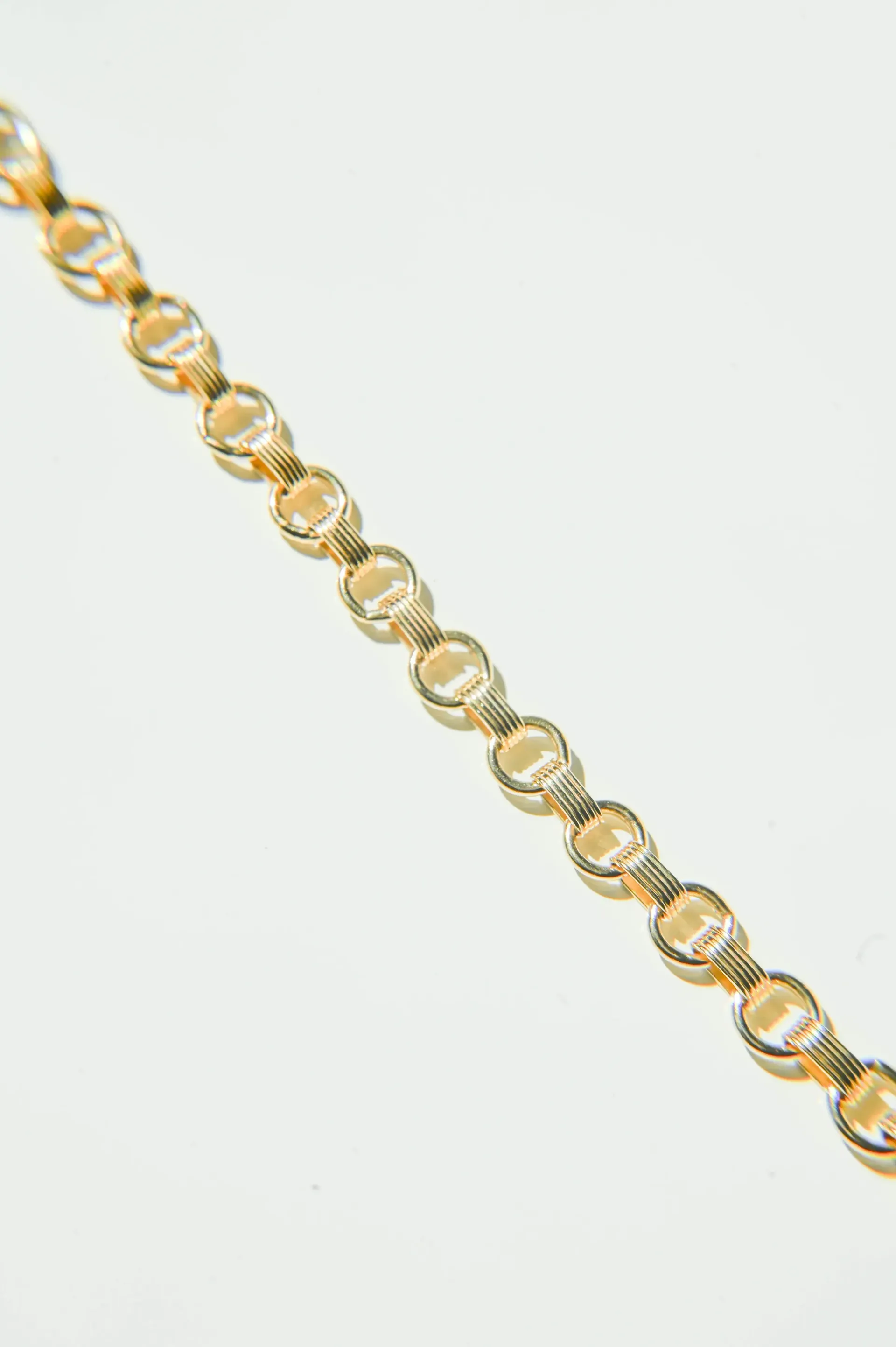A close up of a gold chain on a white background.